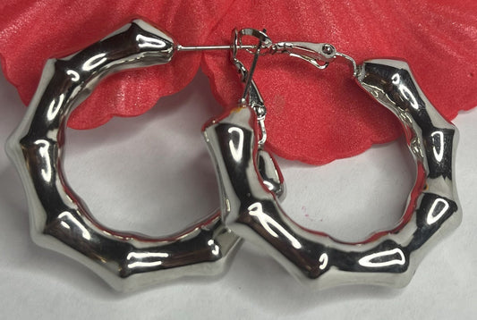 Orecchini Bambù Prezioso placcati argento con texture bambù a cerchio, design naturale elegante su sfondo bianco con fiore rosso decorativo