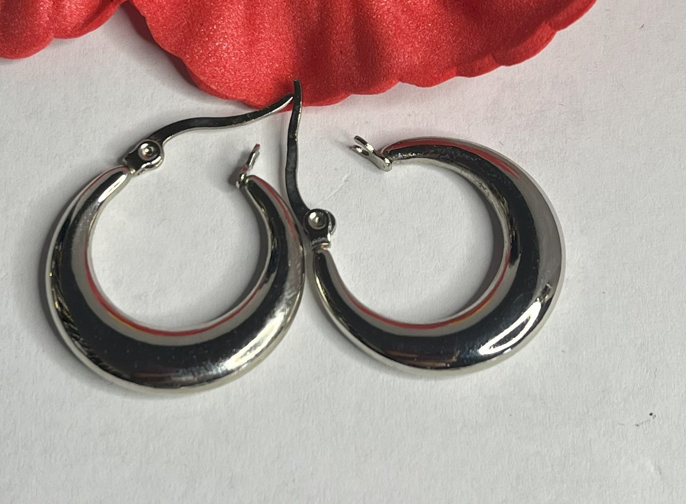 Set di orecchini creoli placcati, due paia in oro e argento, disposti su sfondo neutro con fiore rosso decorativo