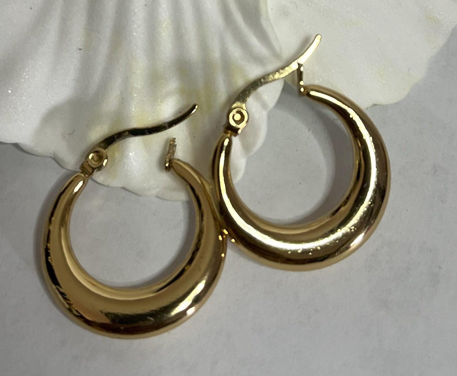 Set di orecchini creoli placcati, due paia in oro e argento, disposti su sfondo neutro con fiore rosso decorativo