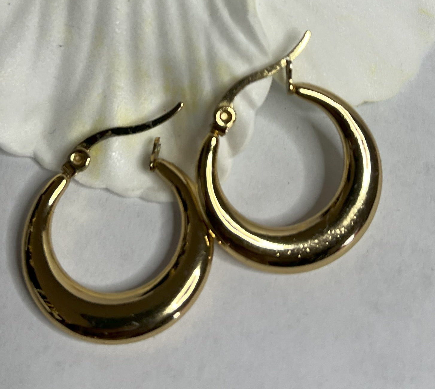 Set di orecchini creoli placcati, due paia in oro e argento, disposti su sfondo neutro con fiore rosso decorativo