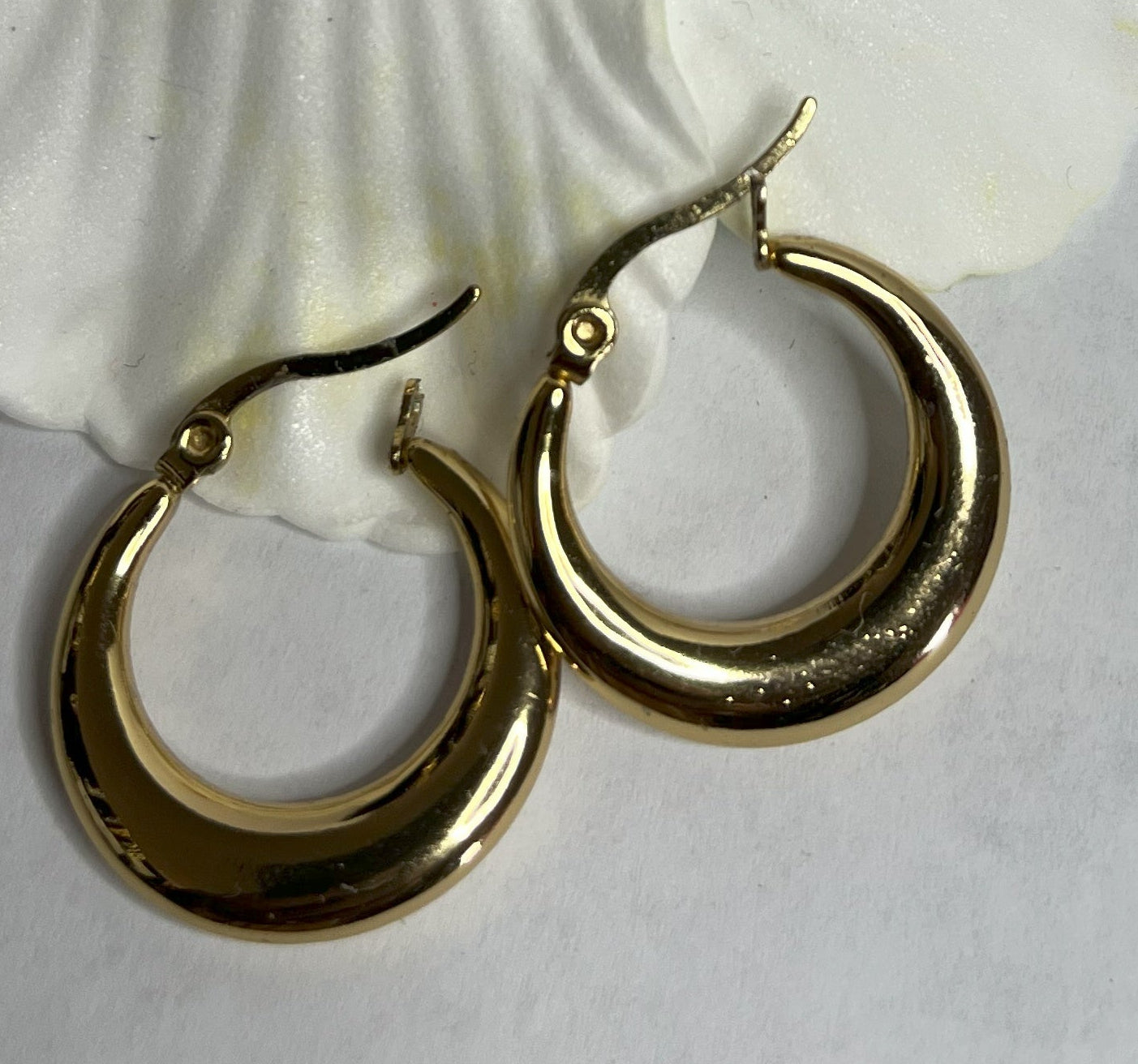 Set di orecchini creoli placcati, due paia in oro e argento, disposti su sfondo neutro con fiore rosso decorativo