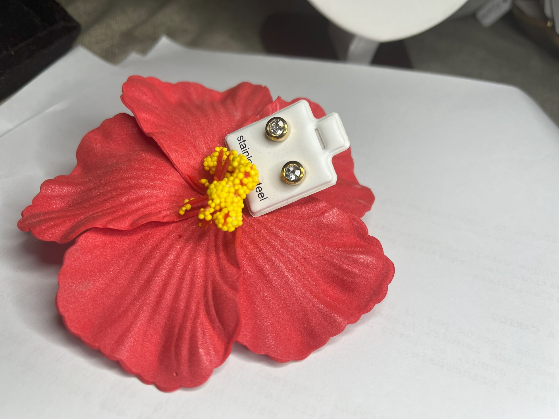Coppia di orecchini punto luce in acciaio placcato su sfondo bianco con fiore rosso decorativo, design elegante a bottone con chiusura a farfallina