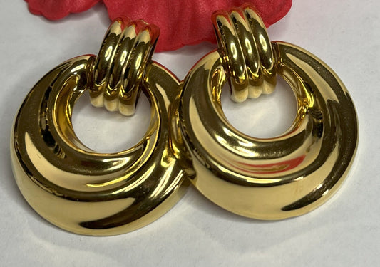 Orecchini dorati vintage anni 80 con design a cerchi concentrici su sfondo neutro