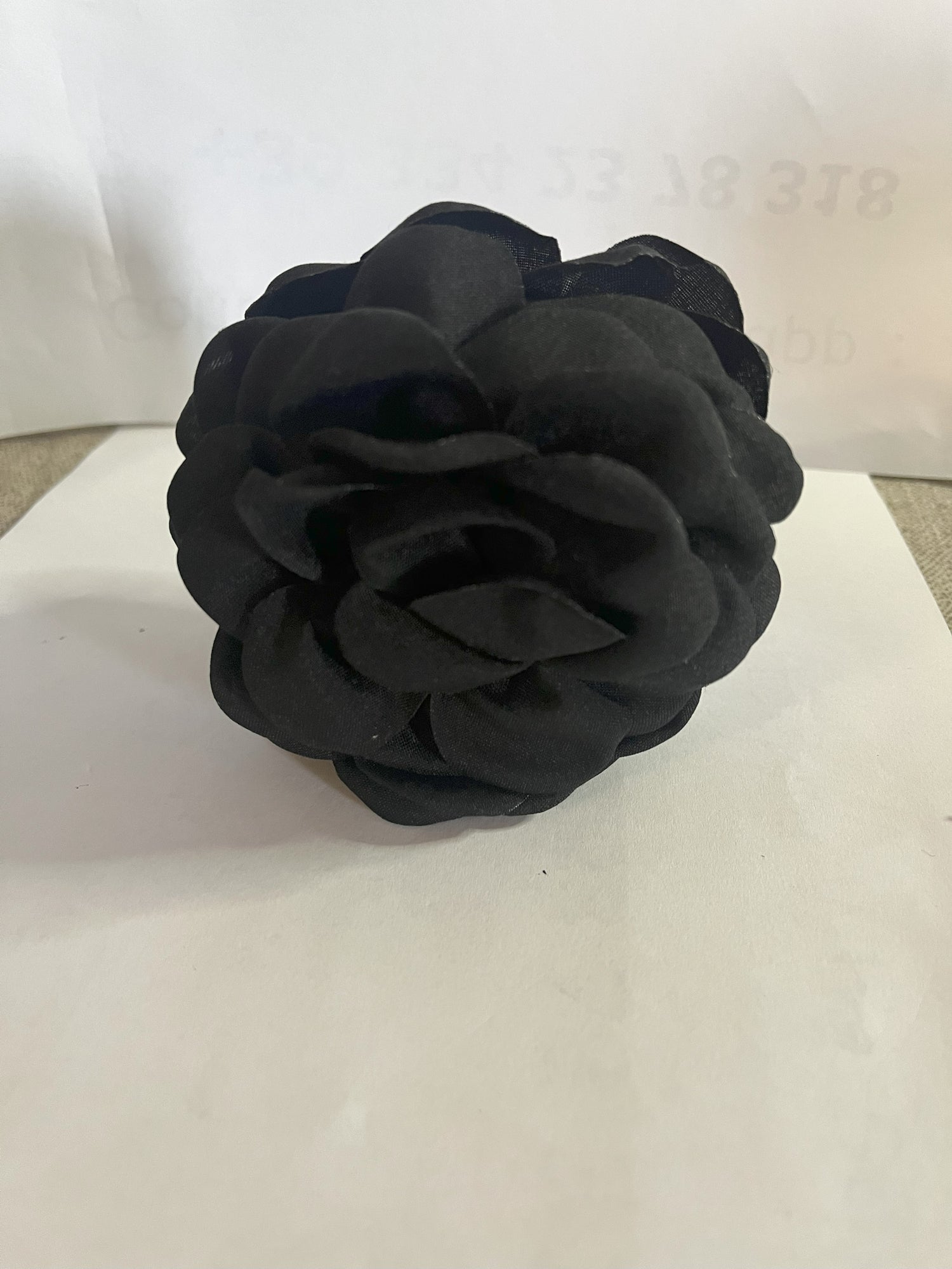 Pinza per capelli a forma di rosa realizzata in tessuto con petali sovrapposti e texture dettagliata, su sfondo neutro