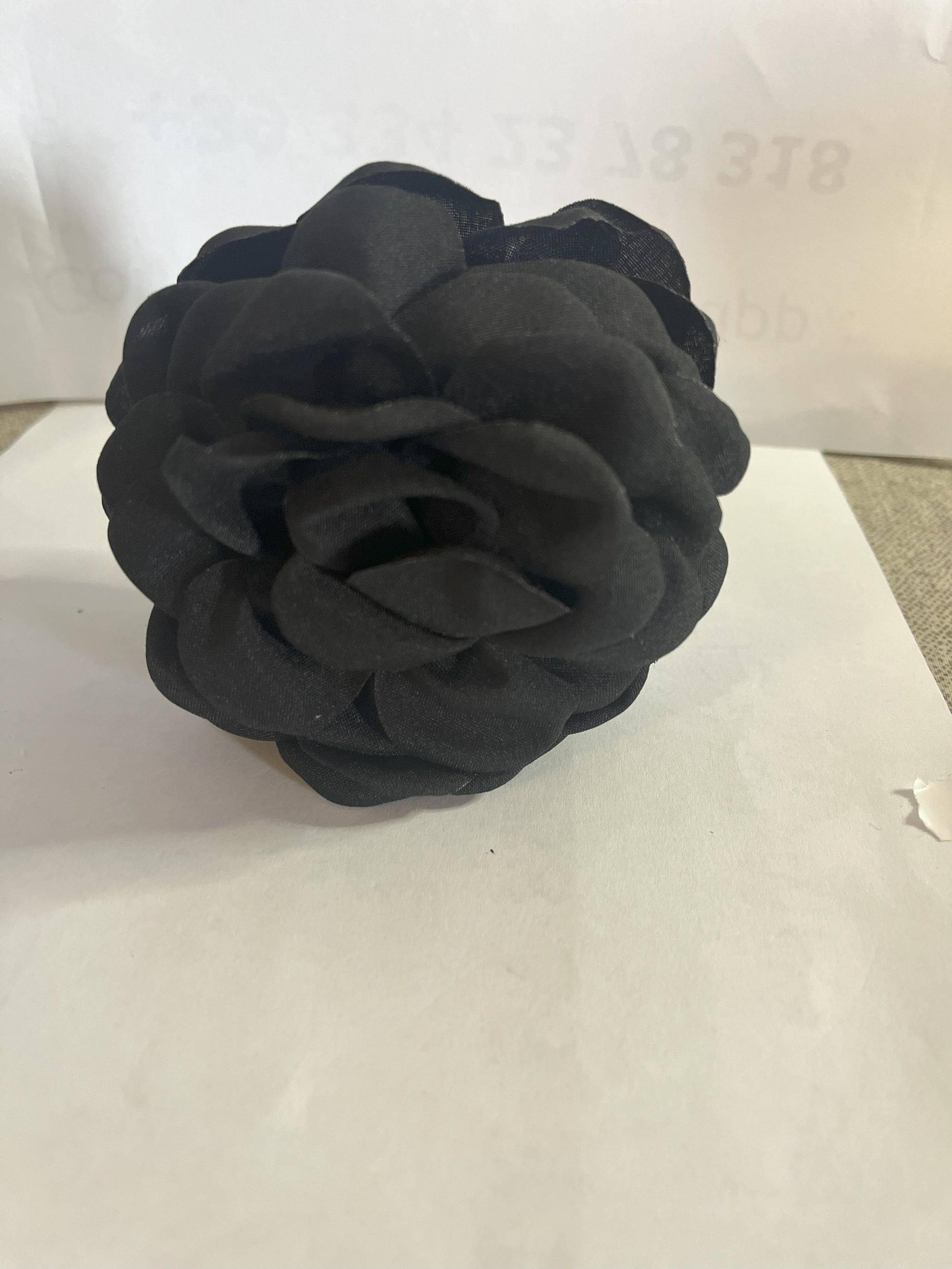 Pinza per capelli a forma di rosa realizzata in tessuto con petali sovrapposti e texture dettagliata, su sfondo neutro