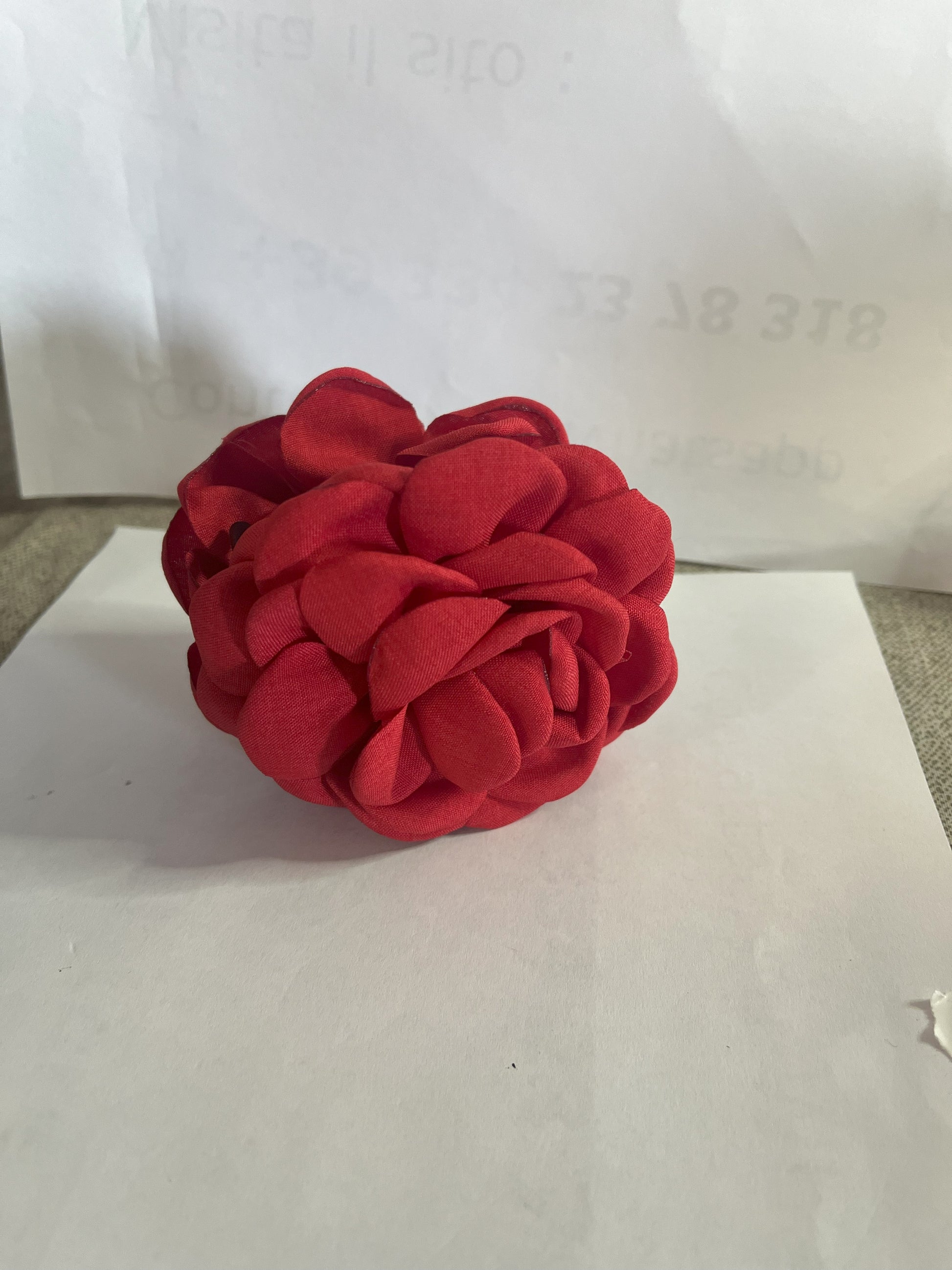 Pinza per capelli a forma di rosa realizzata in tessuto con petali sovrapposti e texture dettagliata, su sfondo neutro