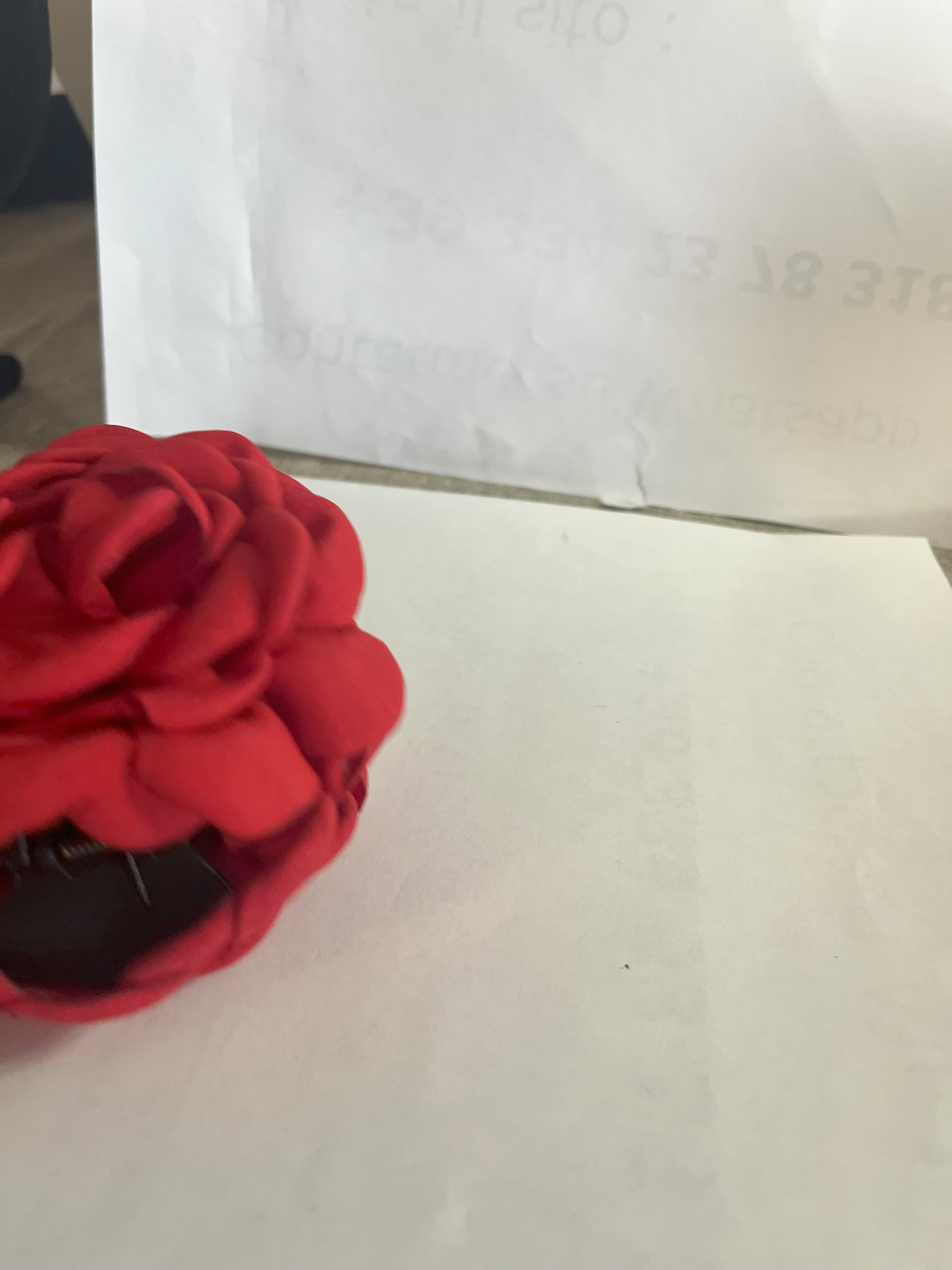 Pinza per capelli a forma di rosa realizzata in tessuto con petali sovrapposti e texture dettagliata, su sfondo neutro