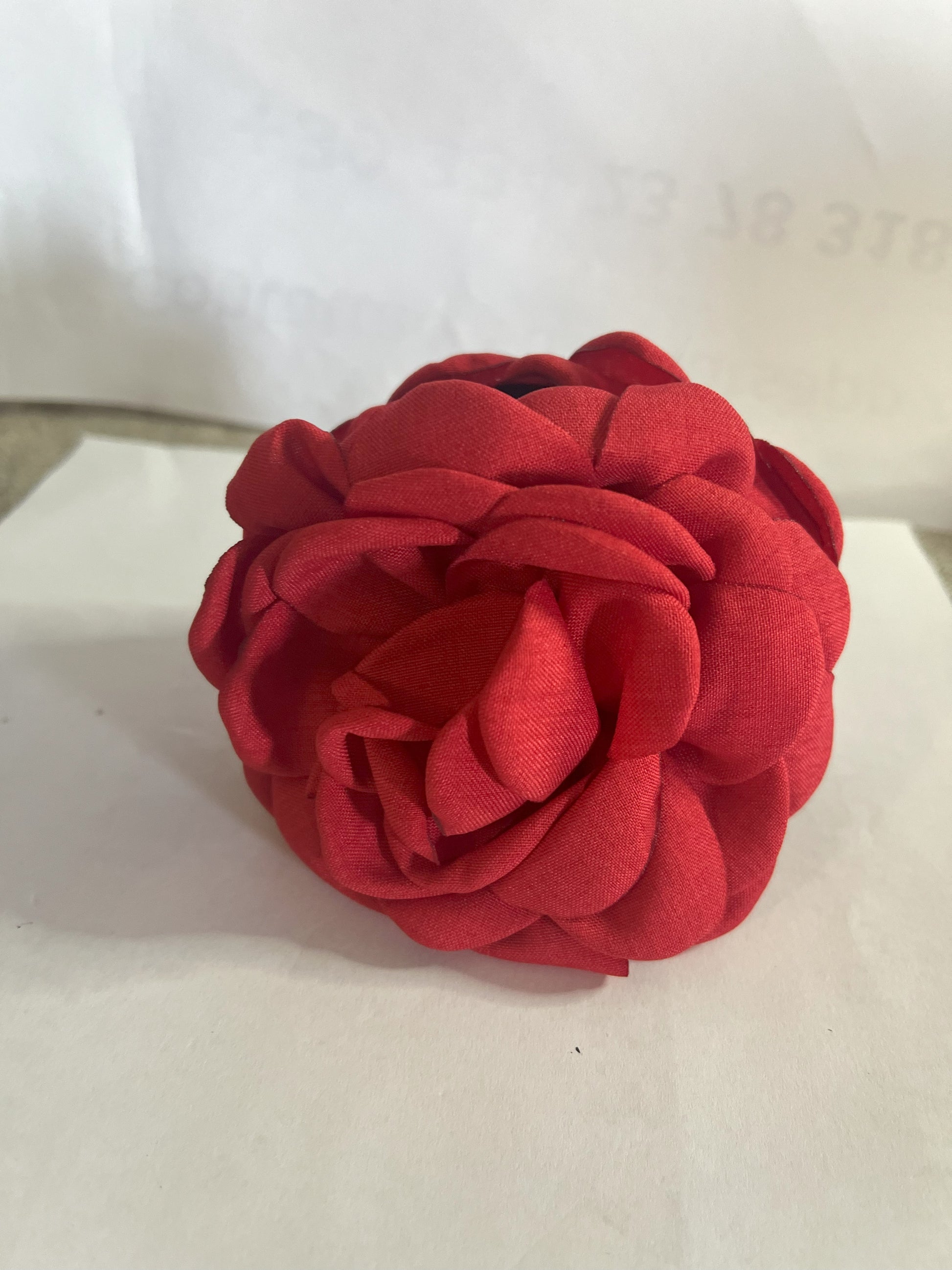 Pinza per capelli a forma di rosa realizzata in tessuto con petali sovrapposti e texture dettagliata, su sfondo neutro