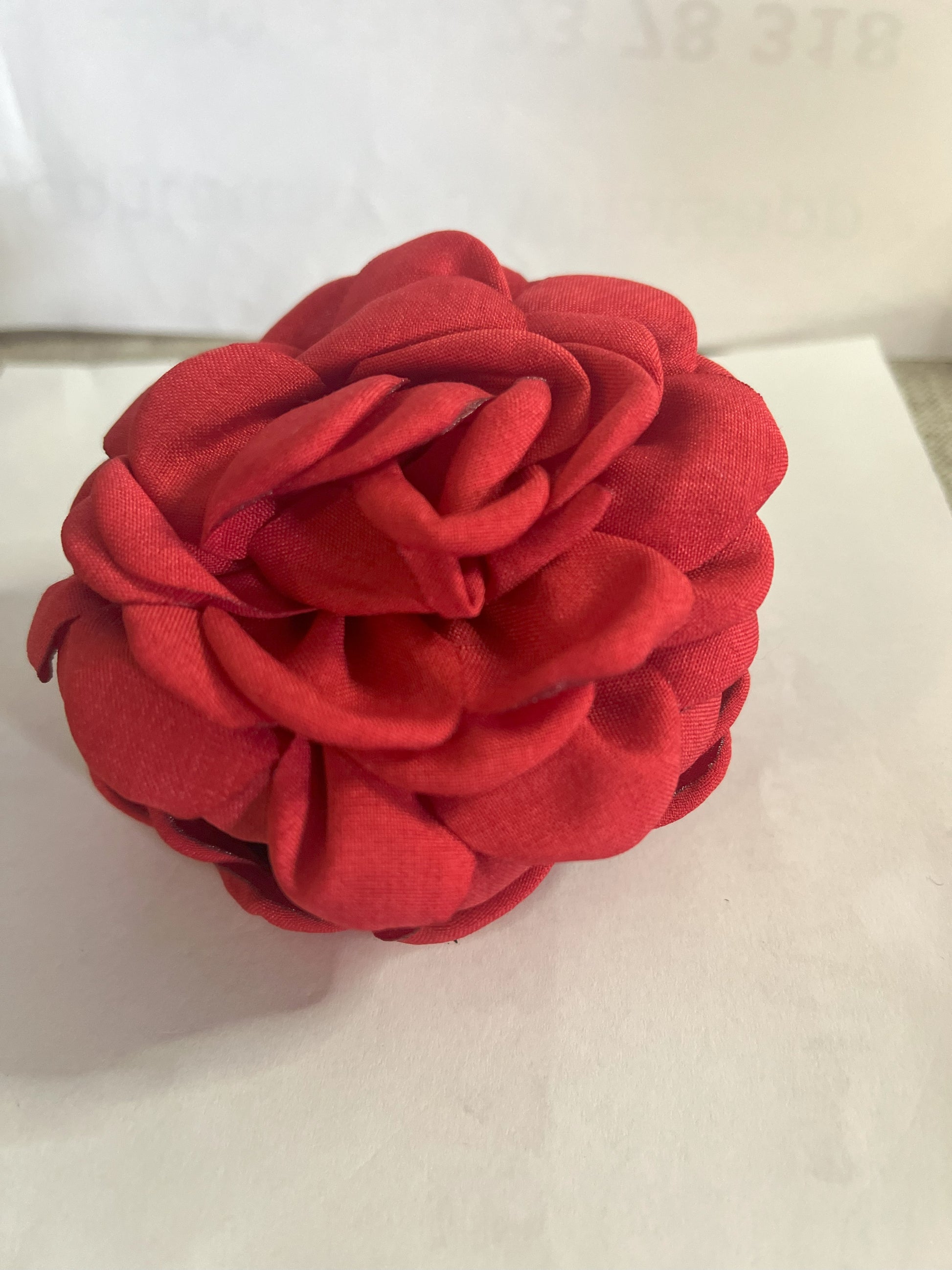 Pinza per capelli a forma di rosa realizzata in tessuto con petali sovrapposti e texture dettagliata, su sfondo neutro