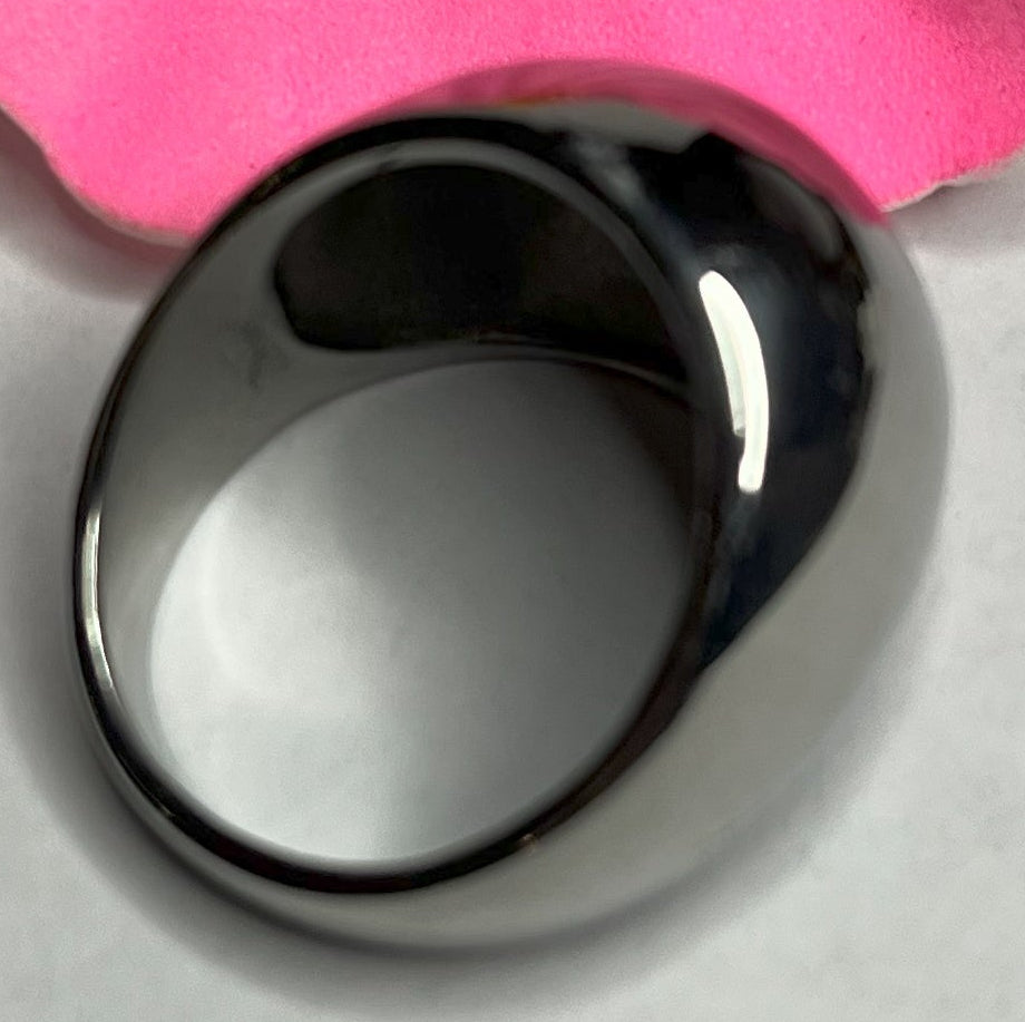 Anello Riflesso Argento in acciaio inossidabile con finitura a specchio lucida, design ovale elegante, fotografato su petalo di fiore rosa che ne esalta la brillantezza
