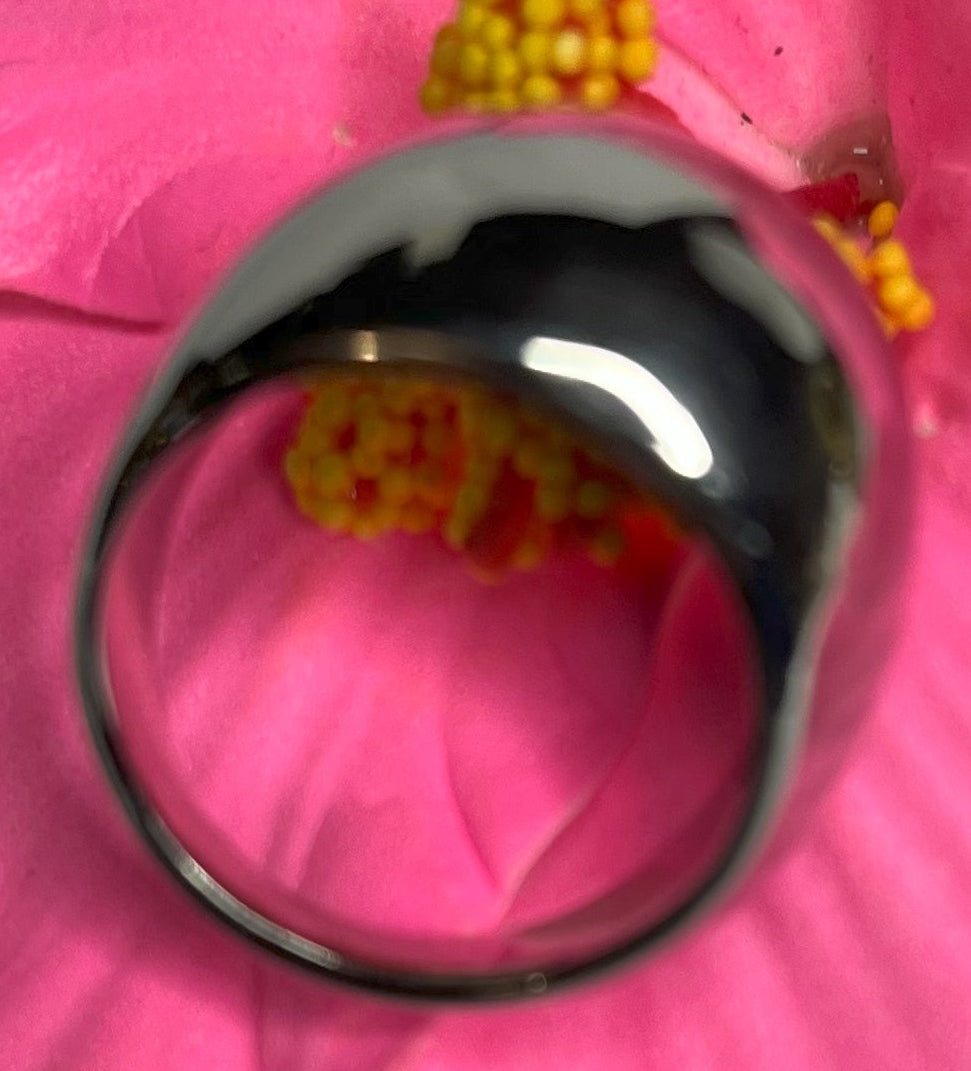 Anello Riflesso Argento in acciaio inossidabile con finitura a specchio lucida, design ovale elegante, fotografato su petalo di fiore rosa che ne esalta la brillantezza