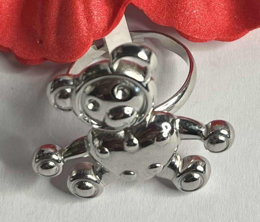 Anello con ciondolo a forma di orsetto, placcato argento, su sfondo bianco con fiore rosso decorativo