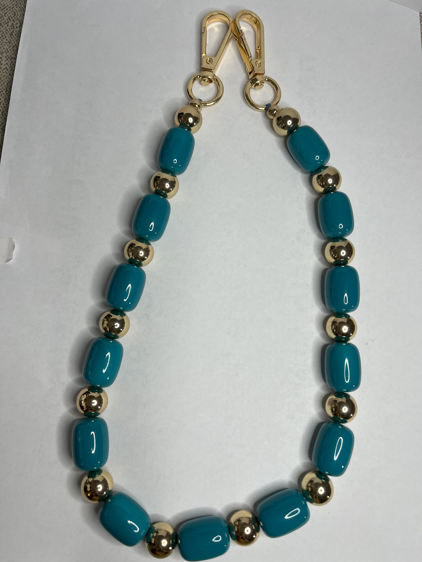 Accessorio multifunzione Oval Multistyle con perle ovali sintetiche fucsia e turchese e dettagli dorati, utilizzabile come collana, tracolla per borsa o accessorio decorativo