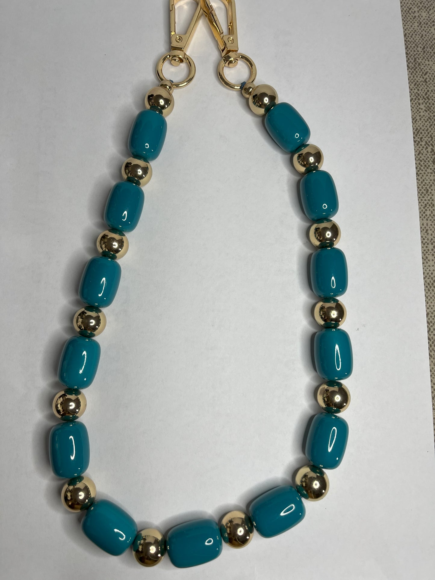 Accessorio multifunzione Oval Multistyle con perle ovali sintetiche fucsia e turchese e dettagli dorati, utilizzabile come collana, tracolla per borsa o accessorio decorativo