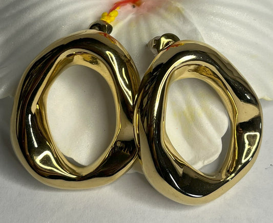 Orecchini Wave premium in due varianti - placcati oro e argento con design organico fluido a forma di onda, fotografati accanto a fiore bianco