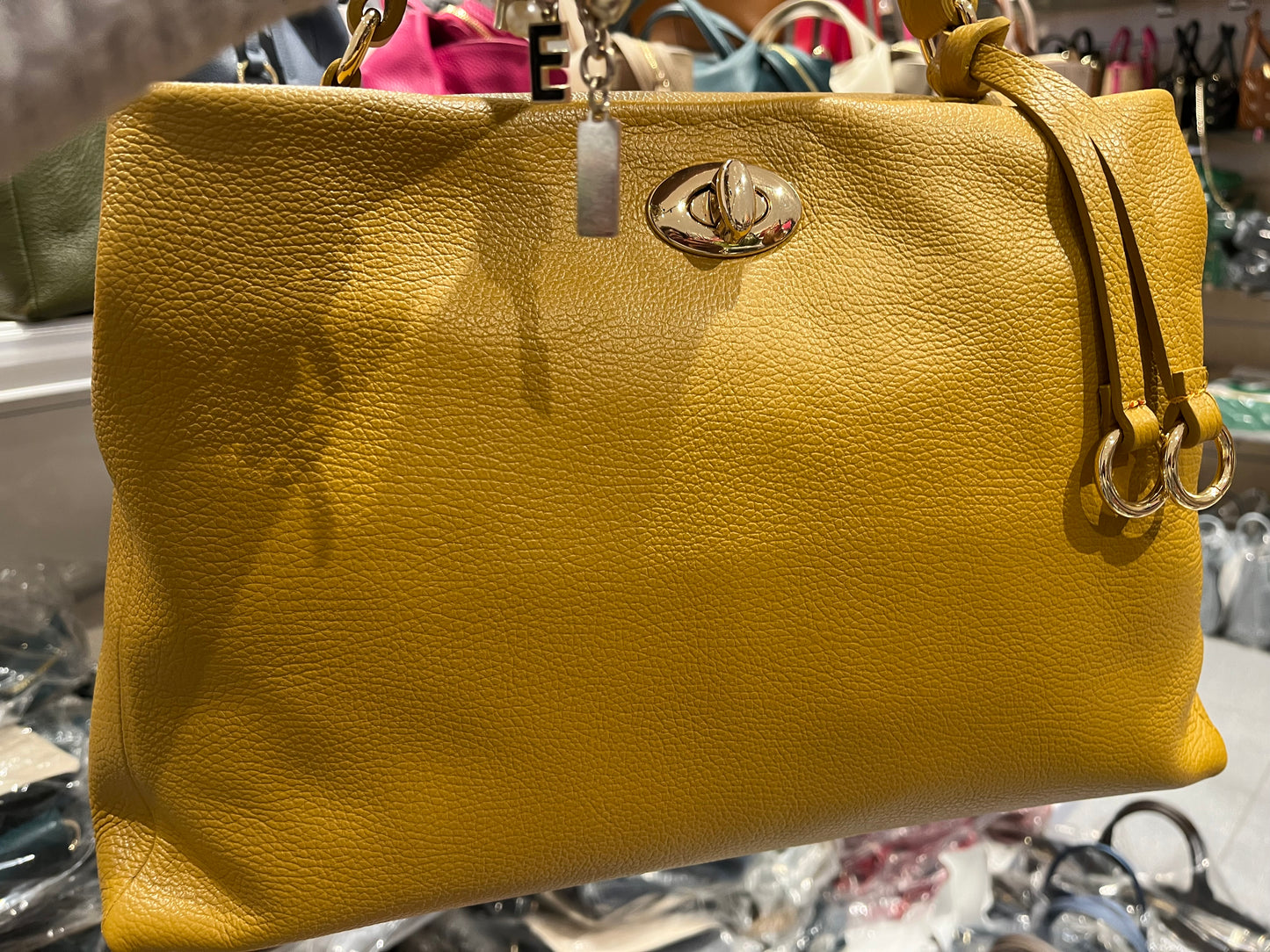 Borsa Sophie in pelle giallo senape con tracolla a catena dorata, chiusura centrale con logo metallico e design morbido e strutturato, perfetta per outfit casual e formali