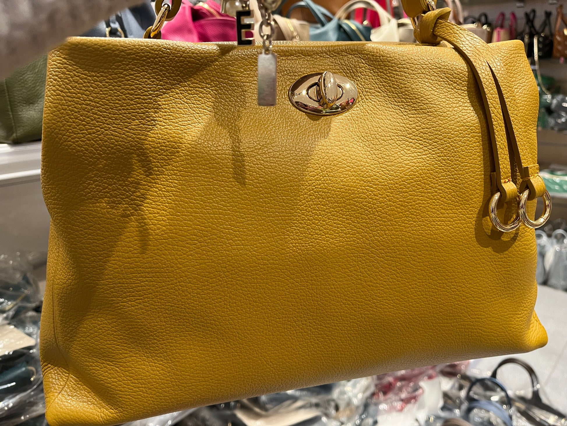 Borsa Sophie in pelle giallo senape con tracolla a catena dorata, chiusura centrale con logo metallico e design morbido e strutturato, perfetta per outfit casual e formali