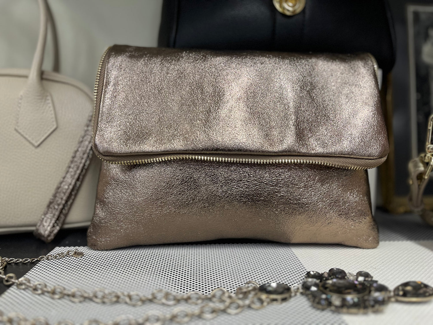 Borsa Cloe color bronzo effetto lucido con chiusura a zip, stile pochette pieghevole.