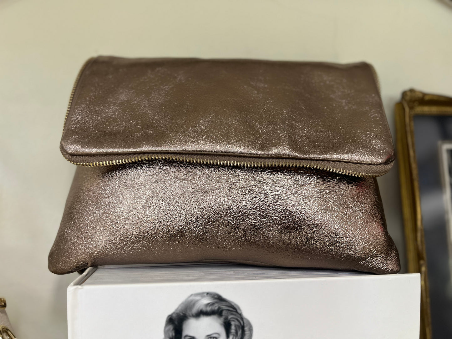 Borsa Cloe color bronzo effetto lucido con chiusura a zip, stile pochette pieghevole.