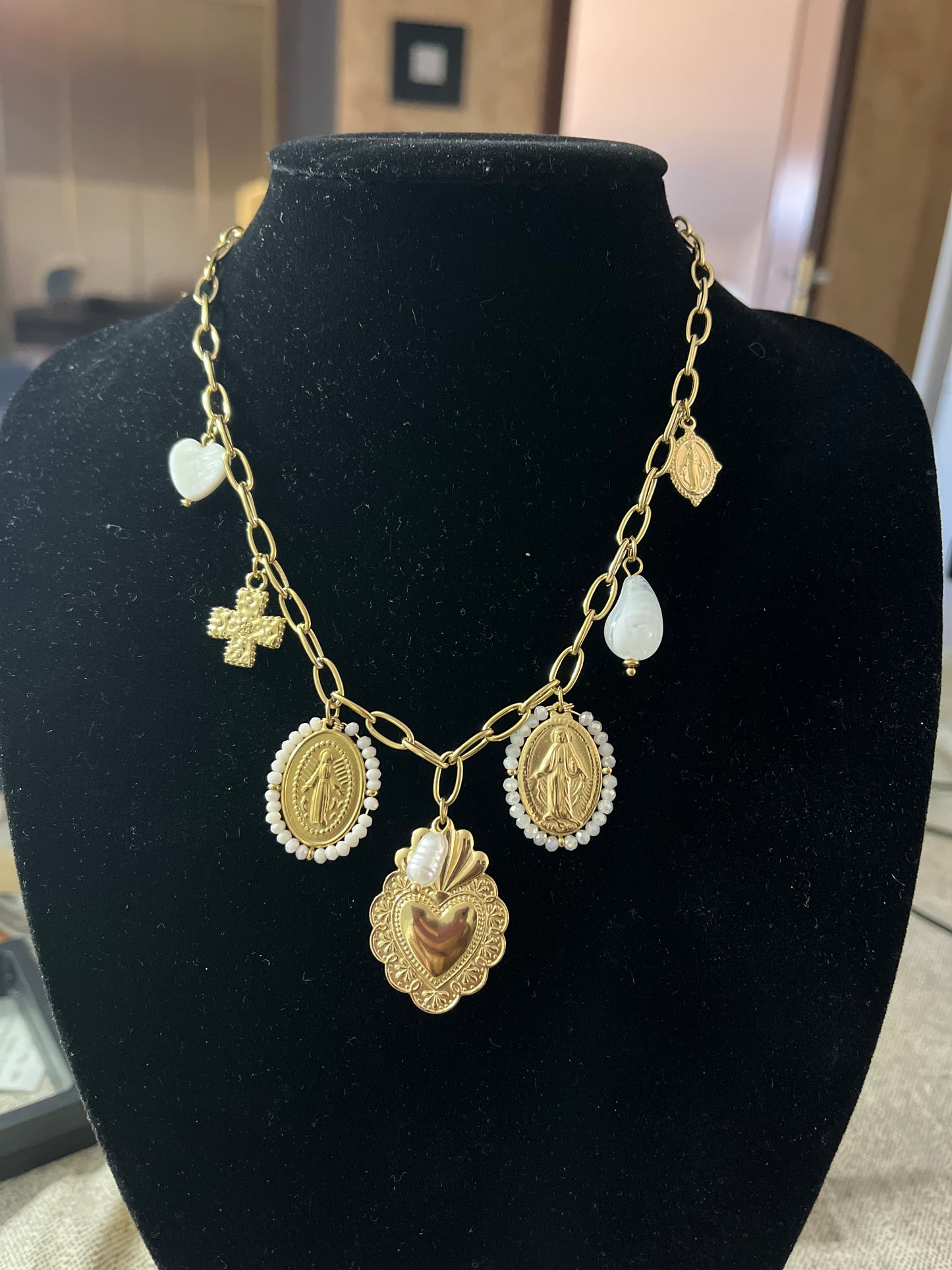 Collana Marzia lunga dorata con ciondoli vintage esposta su busto nero, featuring pendente centrale a cuore e decorazioni ornate in stile classico
