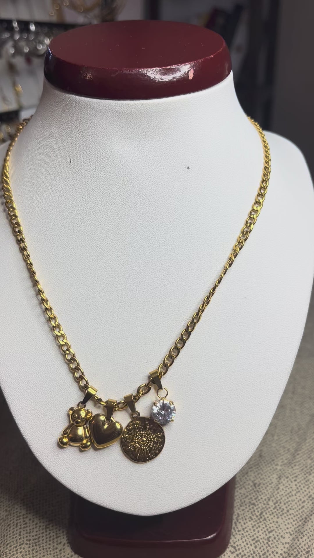 Collana Tesori Dorati in acciaio premium dorato con charm removibili: orsetto, cuore, medaglia decorativa e cristallo brillante su catena elegante. La collana è su espositore bianco