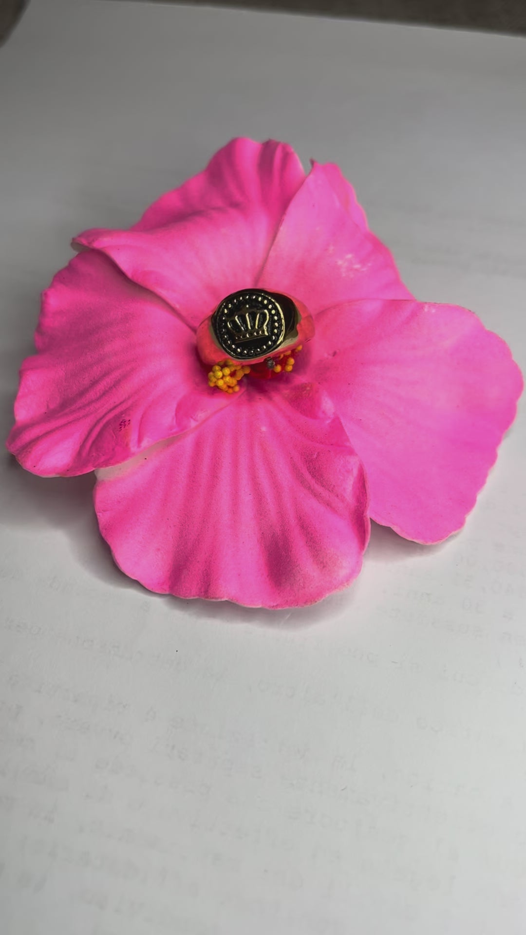 Anello Mignolo Regina in acciaio premium con design regale inciso, variante placcato oro, fotografato su superficie bianca con fiore rosa