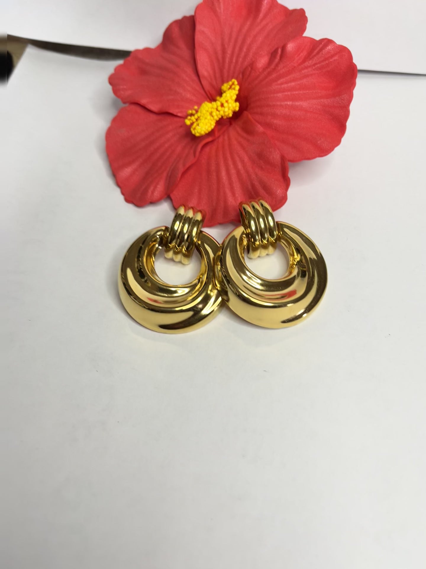 Orecchini dorati vintage anni 80 con design a cerchi concentrici su sfondo neutro