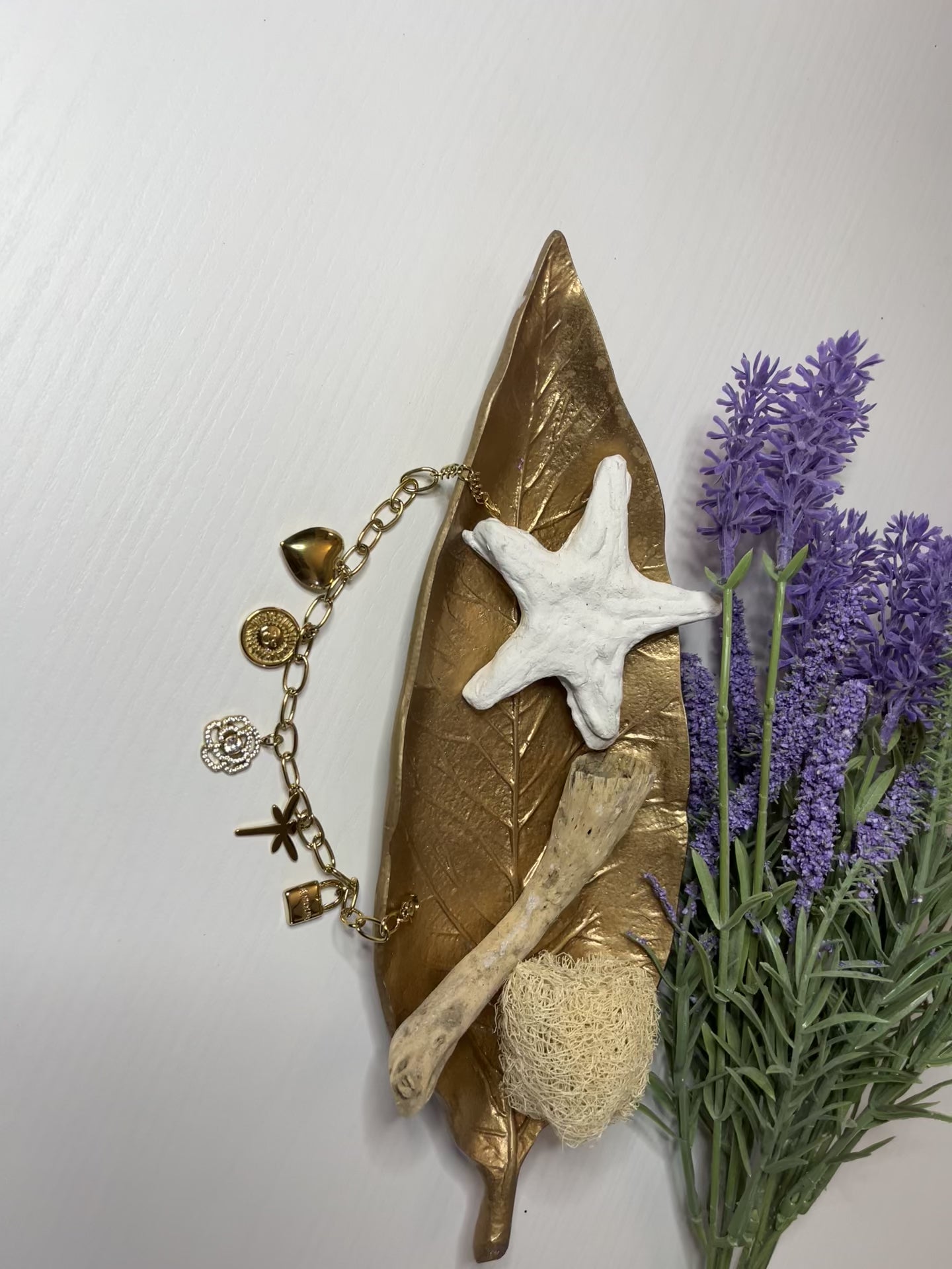 Braccialetto Multi-Charm in oro con ciondoli eleganti su sfondo neutro