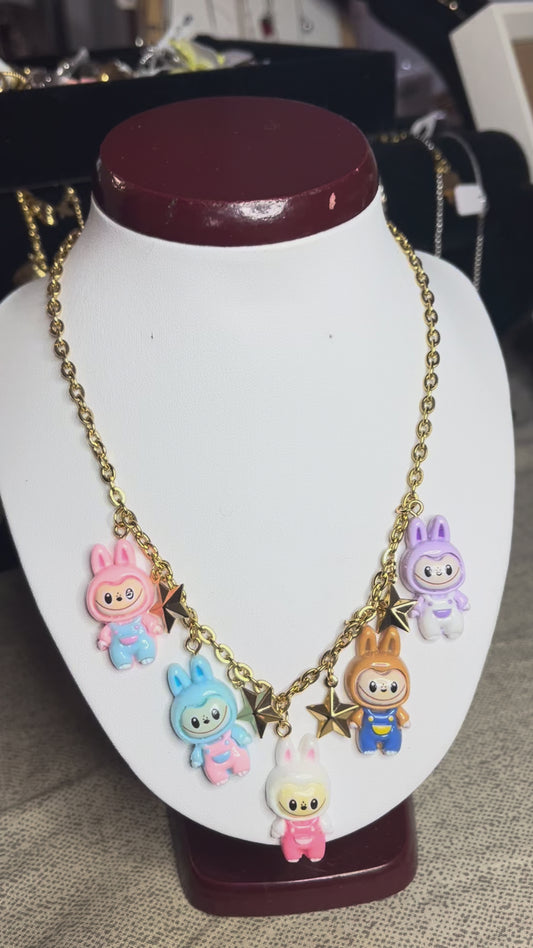 Collana con catena dorata e charms kawaii colorati a forma di personaggi cute, esposta su busto bianco