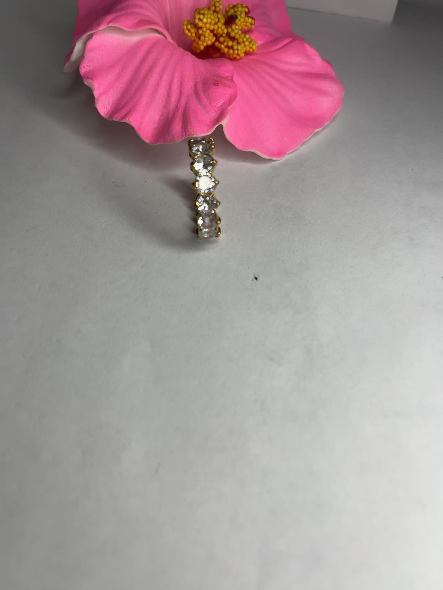 Anello Elegance Wide con fascia larga placcata oro, design minimalista elegante esposto su fiore rosa decorativo