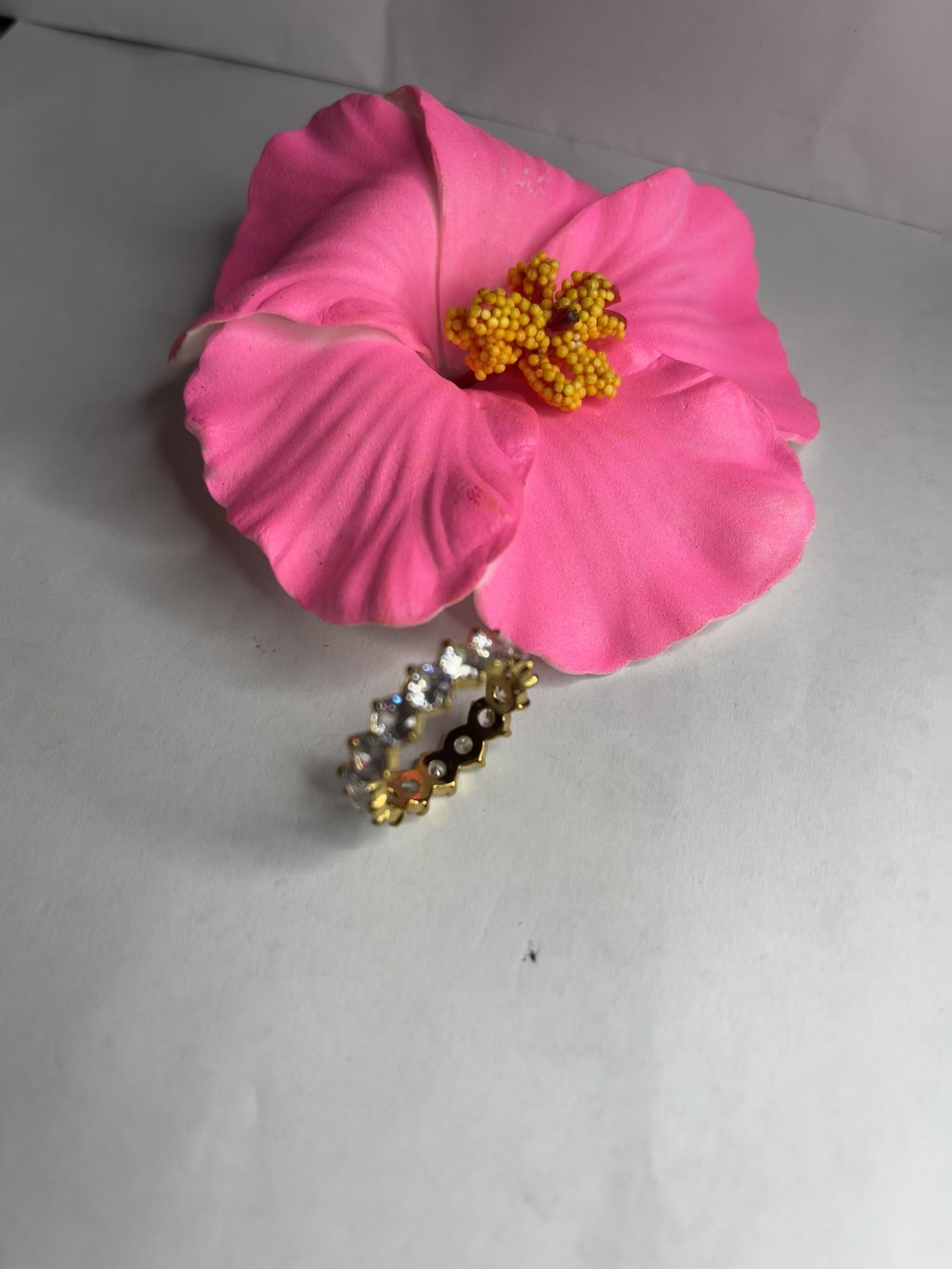 Anello Elegance Wide con fascia larga placcata oro, design minimalista elegante esposto su fiore rosa decorativo