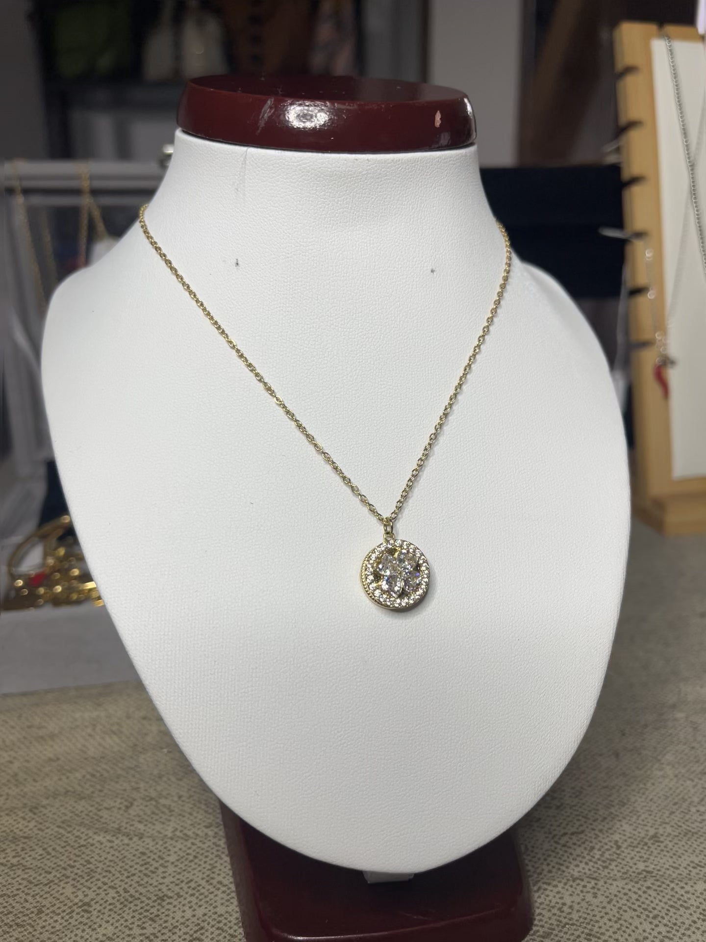 Collana Wish con elegante ciondolo quadrifoglio dorato e dettagli scintillanti, esposta su busto porta gioielli bianco