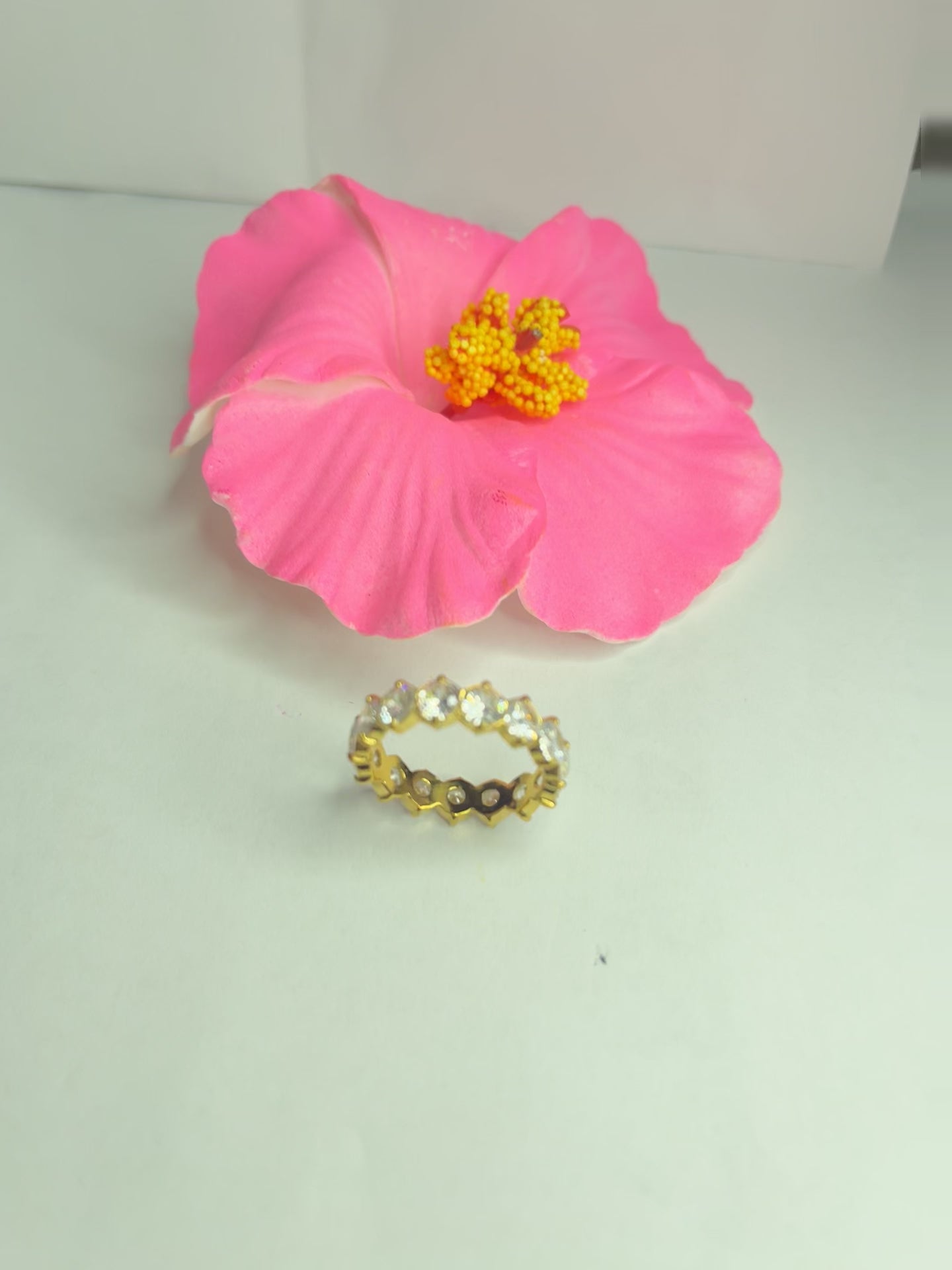 Anello Elegance Wide con fascia larga placcata oro, design minimalista elegante esposto su fiore rosa decorativo
