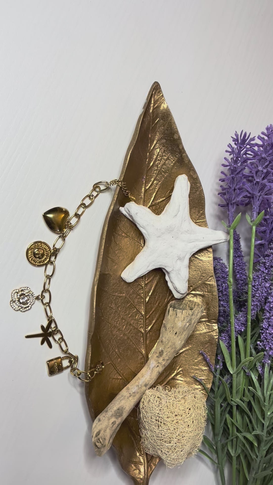 Braccialetto Multi-Charm in oro con ciondoli eleganti su sfondo neutro