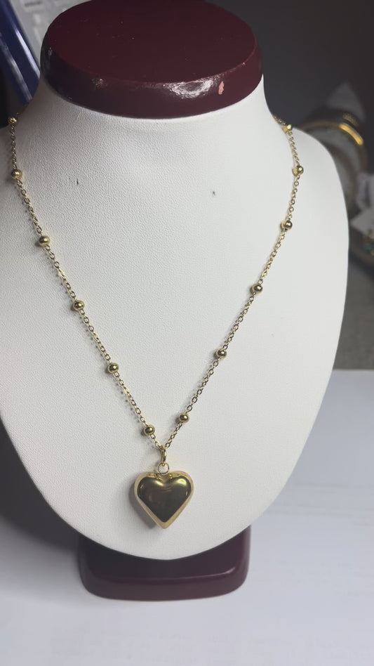 Collana Allegra in acciaio premium con catena decorata da sfere e ciondolo cuore, variante placcato oro, esposta su busto espositore bianco