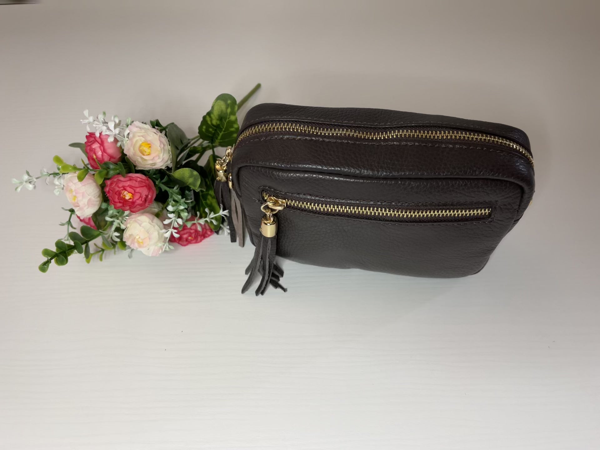 Borsa Mogano Premium in vera pelle testa di moro Made in Italy con doppia cerniera dorata, nappa decorativa e tracolla intrecciata regolabile, fotografata su superficie bianca