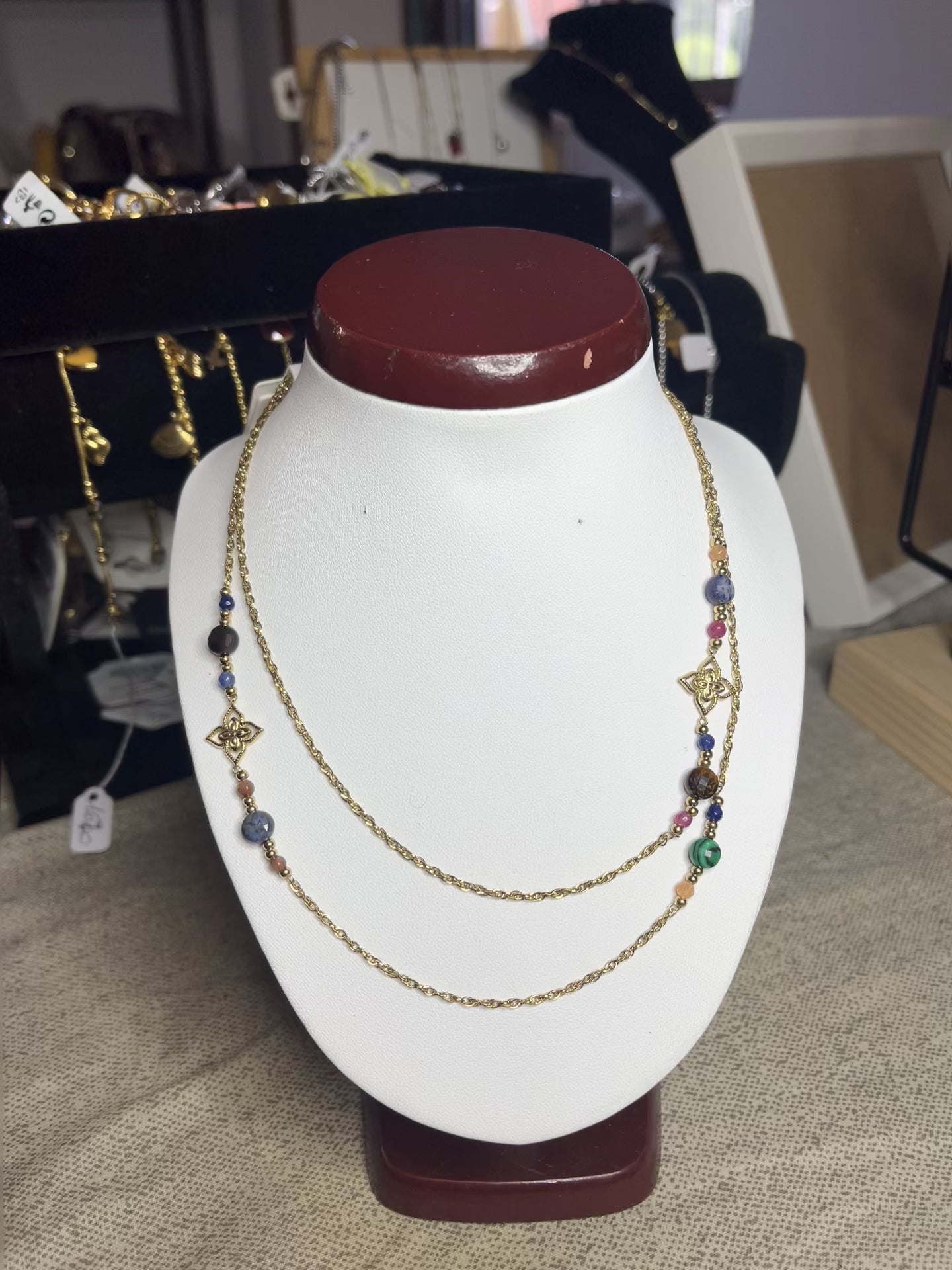 Collana doppio giro in acciaio inossidabile con pietre di agata rosse o verdi/azzurre ciondolo decorativo, esposta su busto bianco