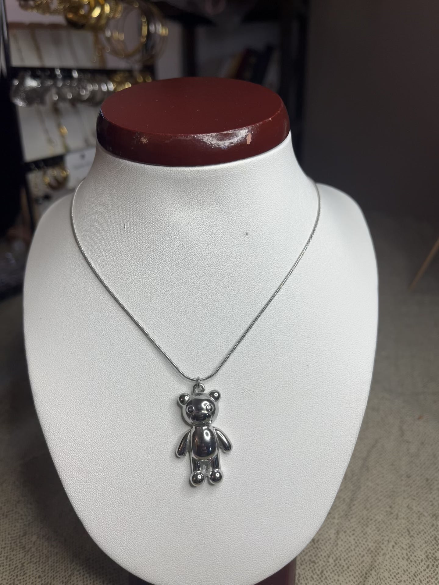 Collana Orsetto dei Sogni in acciaio premium con delicato ciondolo orsetto, variante placcato argento, esposta su busto espositore