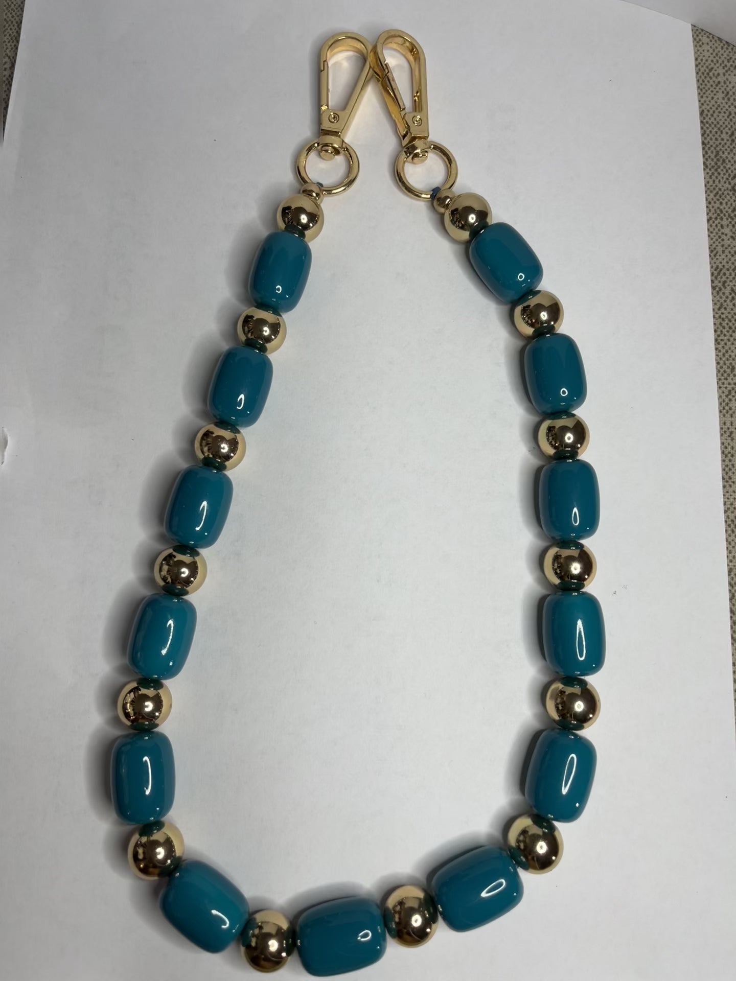 Accessorio multifunzione Oval Multistyle con perle ovali sintetiche fucsia e turchese e dettagli dorati, utilizzabile come collana, tracolla per borsa o accessorio decorativo