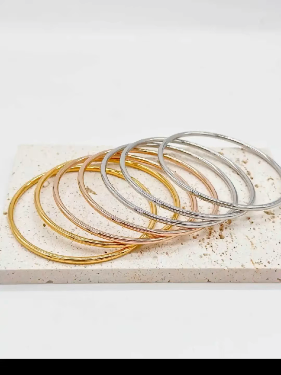 Set di bracciali rigidi sottili in oro, argento e oro rosa su base in marmo