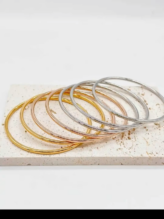 Set di bracciali rigidi sottili in oro, argento e oro rosa su base in marmo