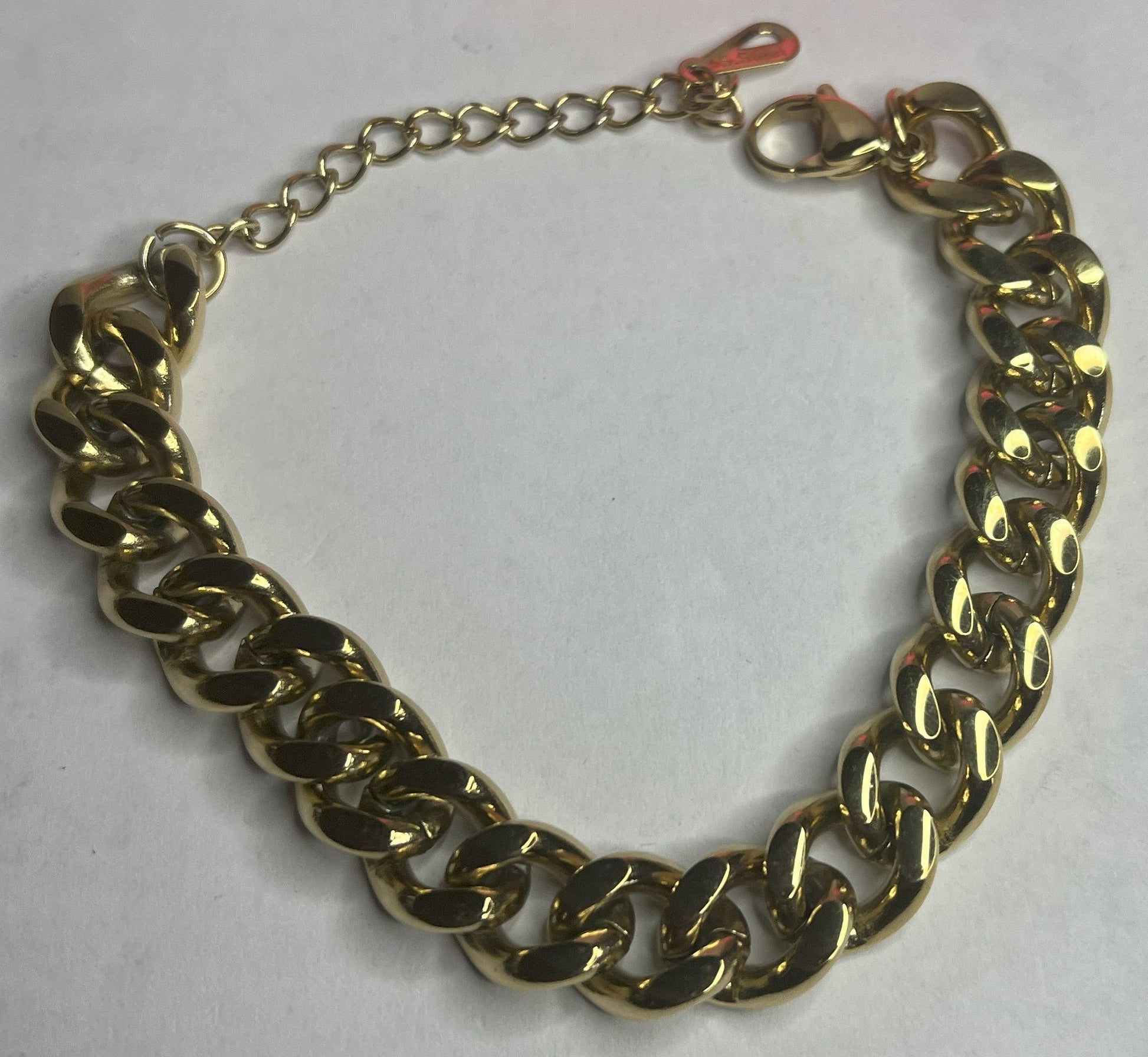 Bracciale Bold Chain placcato oro con maglie chunky grandi su sfondo grigio con petali rosa