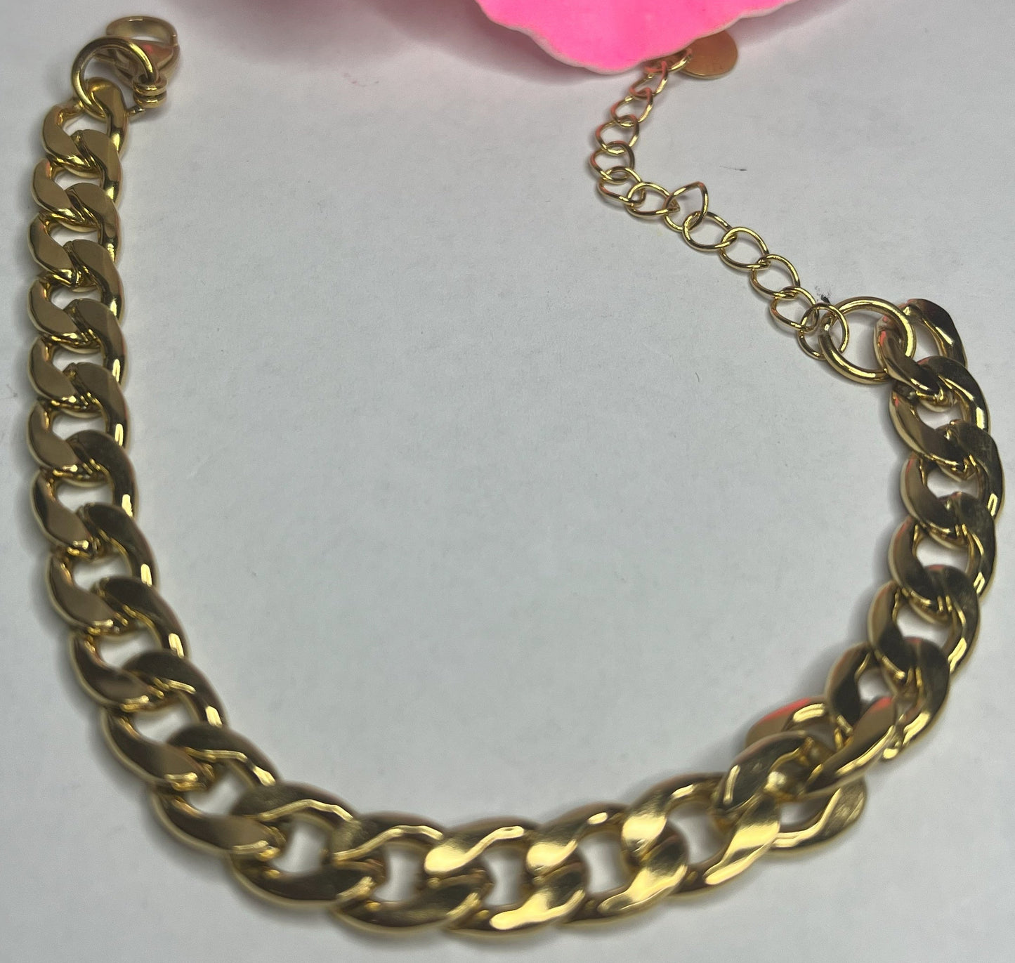 Bracciale Bold Chain placcato oro con maglie chunky grandi su sfondo grigio con petali rosa