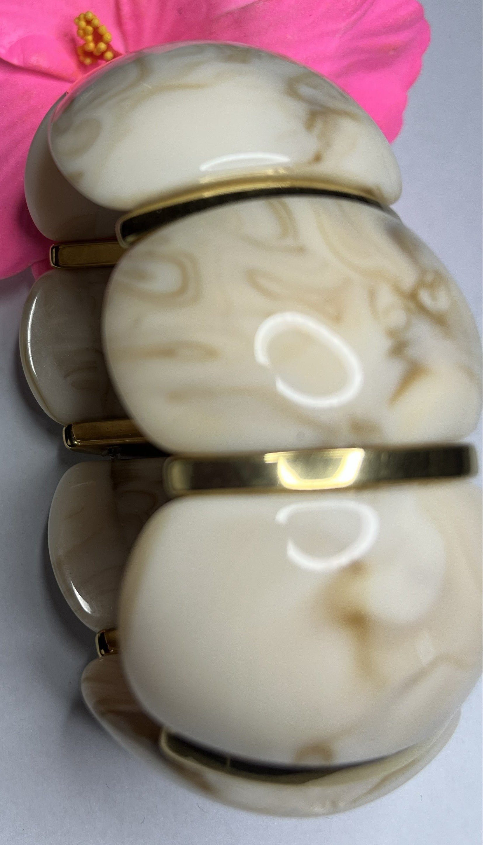 Bracciale effetto marmo in resina con dettagli oro su fiore rosa.