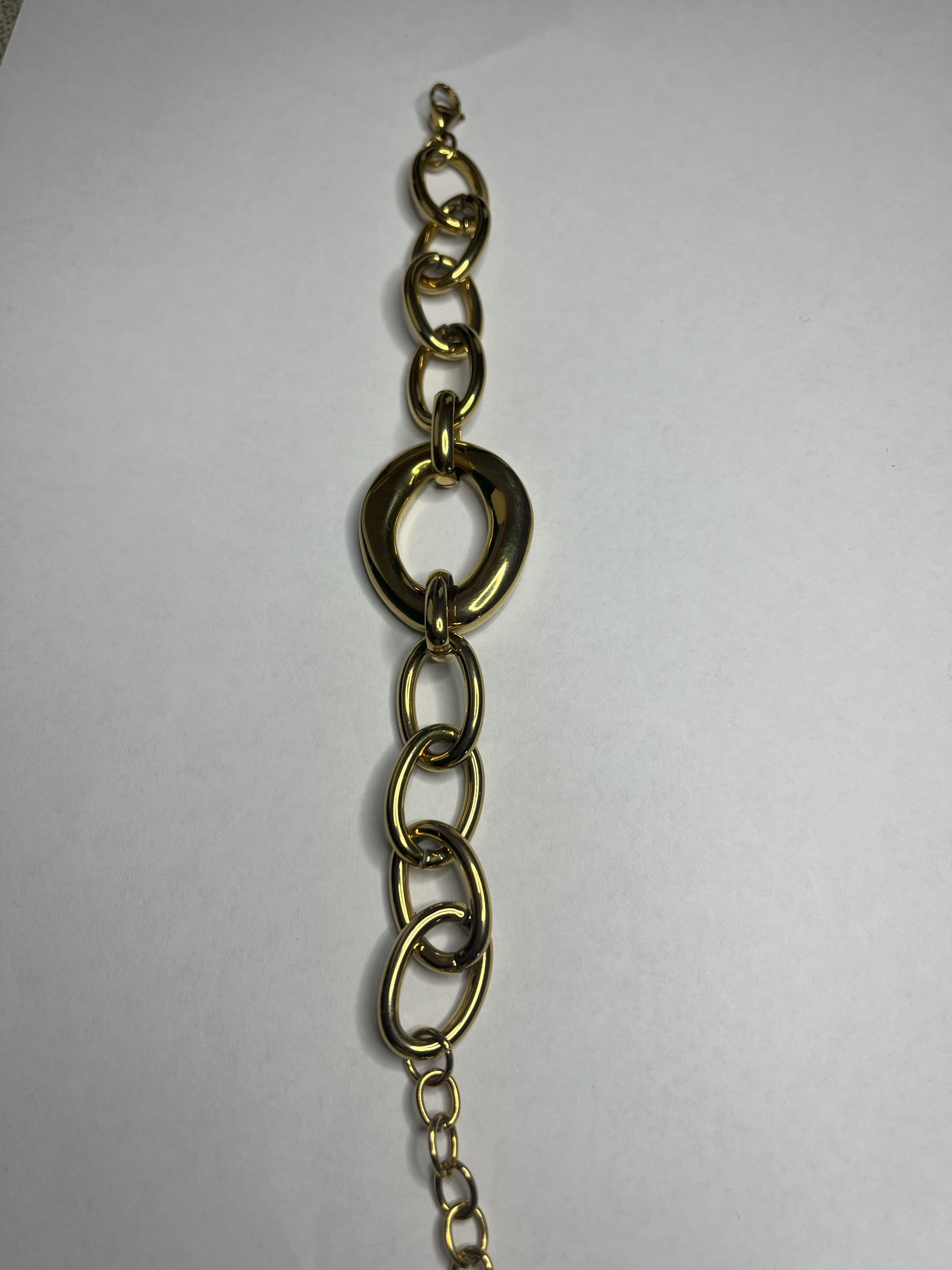 Bracciale Gold Evolution in acciaio 316L placcato oro con maglie graduate e anello centrale statement, su sfondo grigio neutro