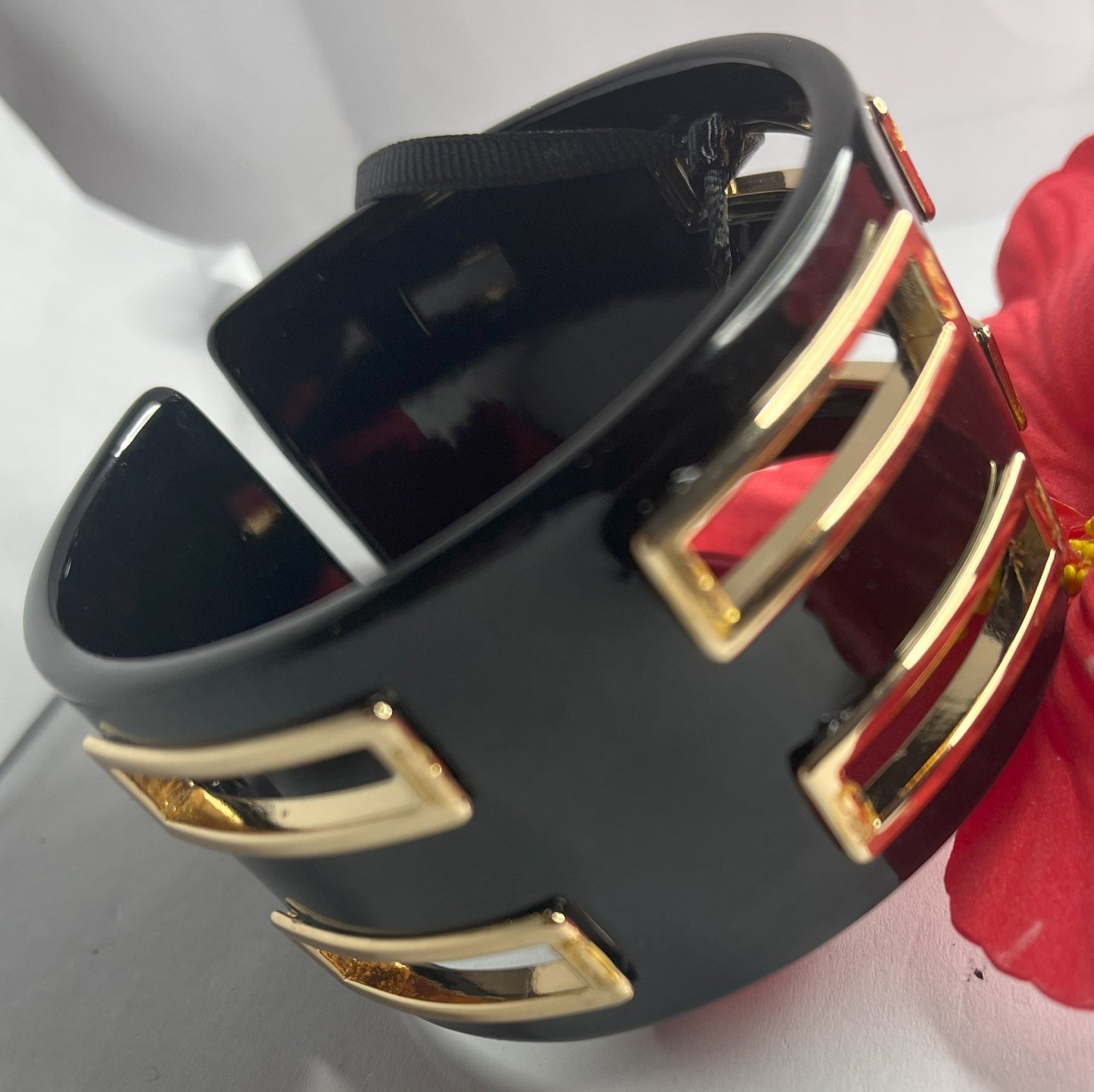 Bracciale rigido Golden Fusion nero con inserti geometrici placcati oro, design moderno ed elegante su sfondo bianco
