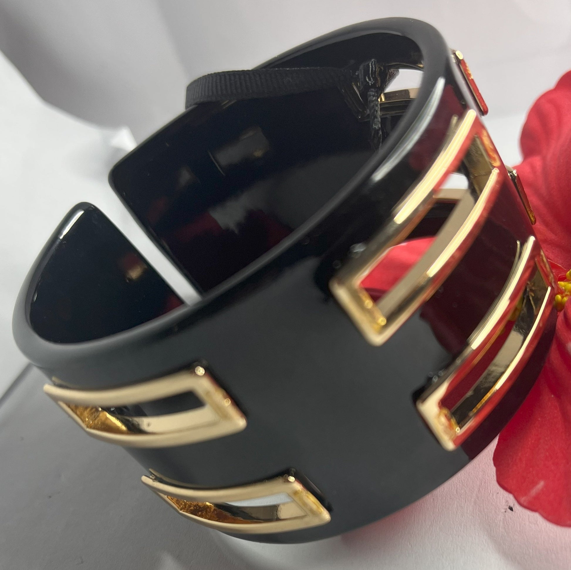 Bracciale rigido Golden Fusion nero con inserti geometrici placcati oro, design moderno ed elegante su sfondo bianco