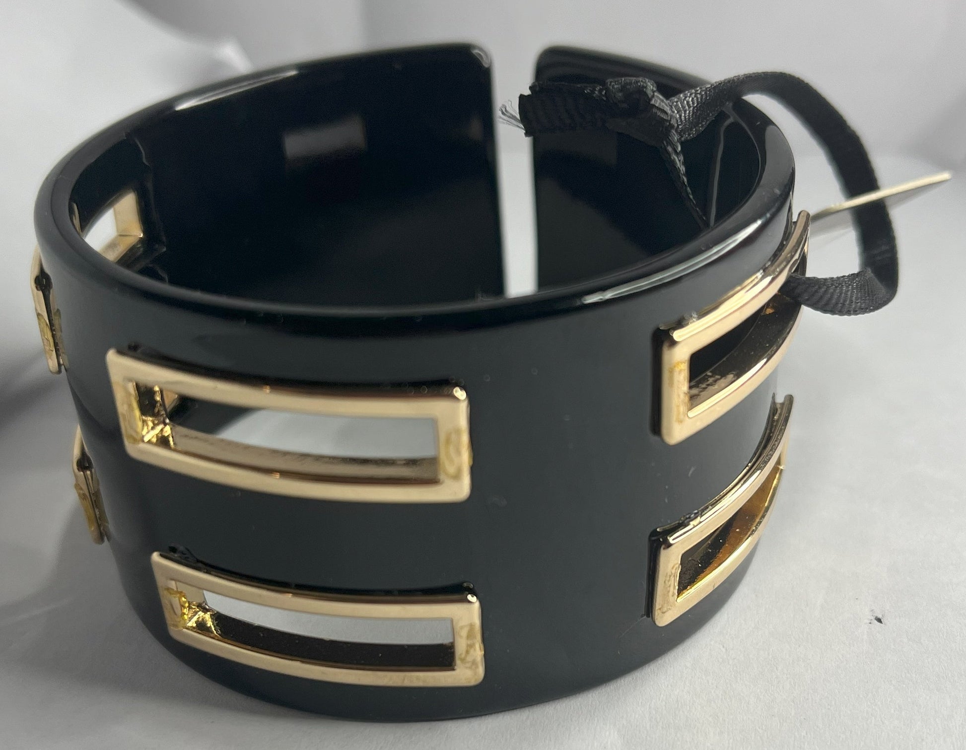 Bracciale rigido Golden Fusion nero con inserti geometrici placcati oro, design moderno ed elegante su sfondo bianco