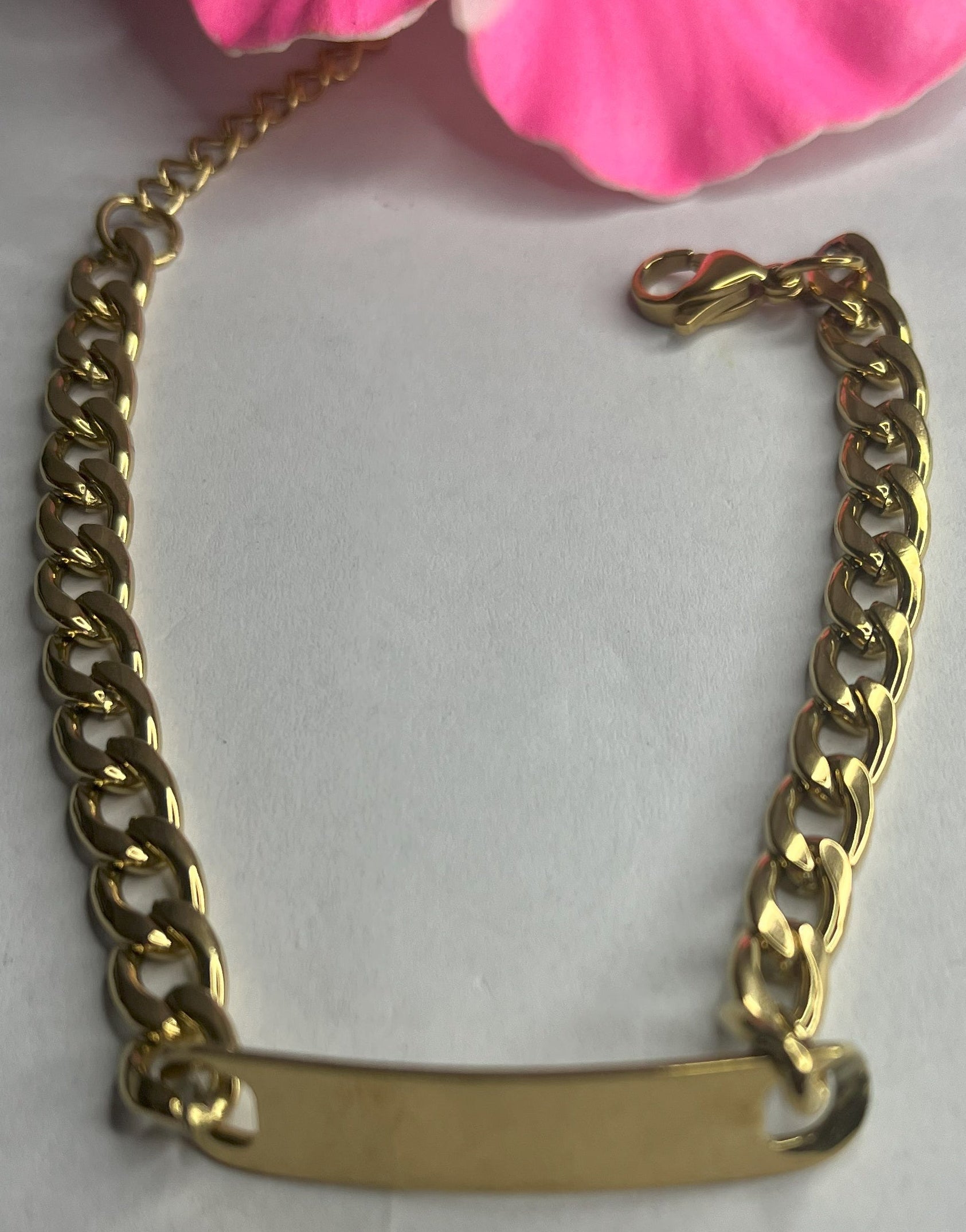 Bracciale Golden Thread sottile placcato oro con maglia fine delicata su sfondo grigio con petali rosa