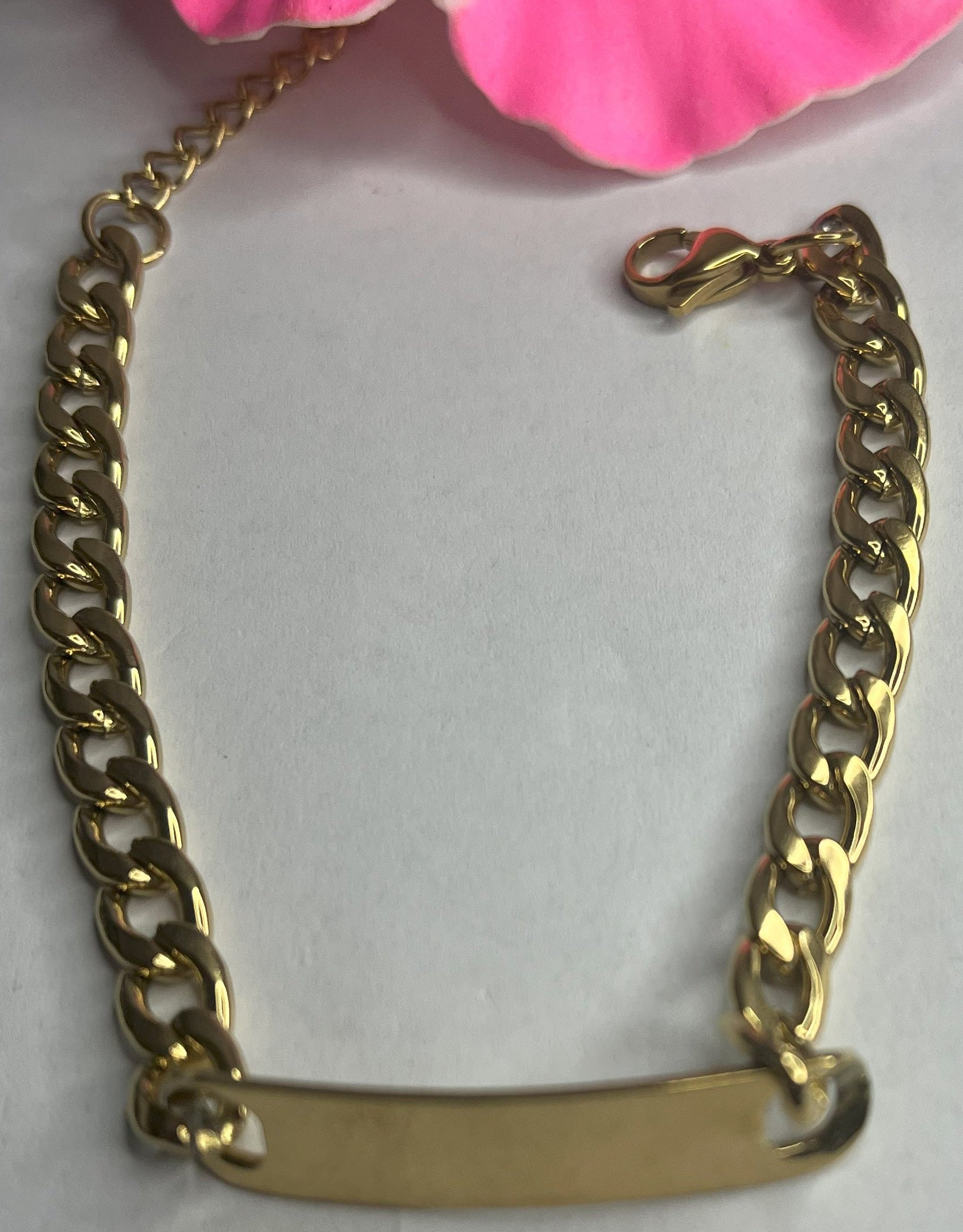 Bracciale Golden Thread sottile placcato oro con maglia fine delicata su sfondo grigio con petali rosa